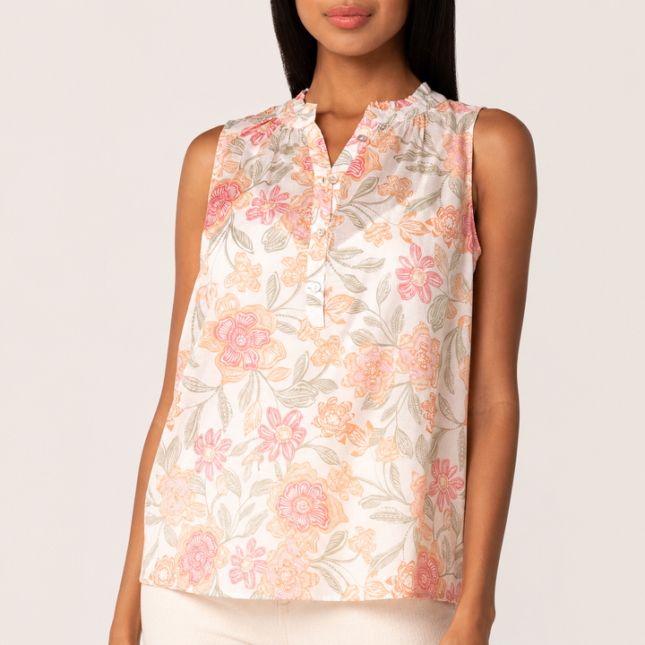 Woman wearing a sleeveless floral top on a plain background