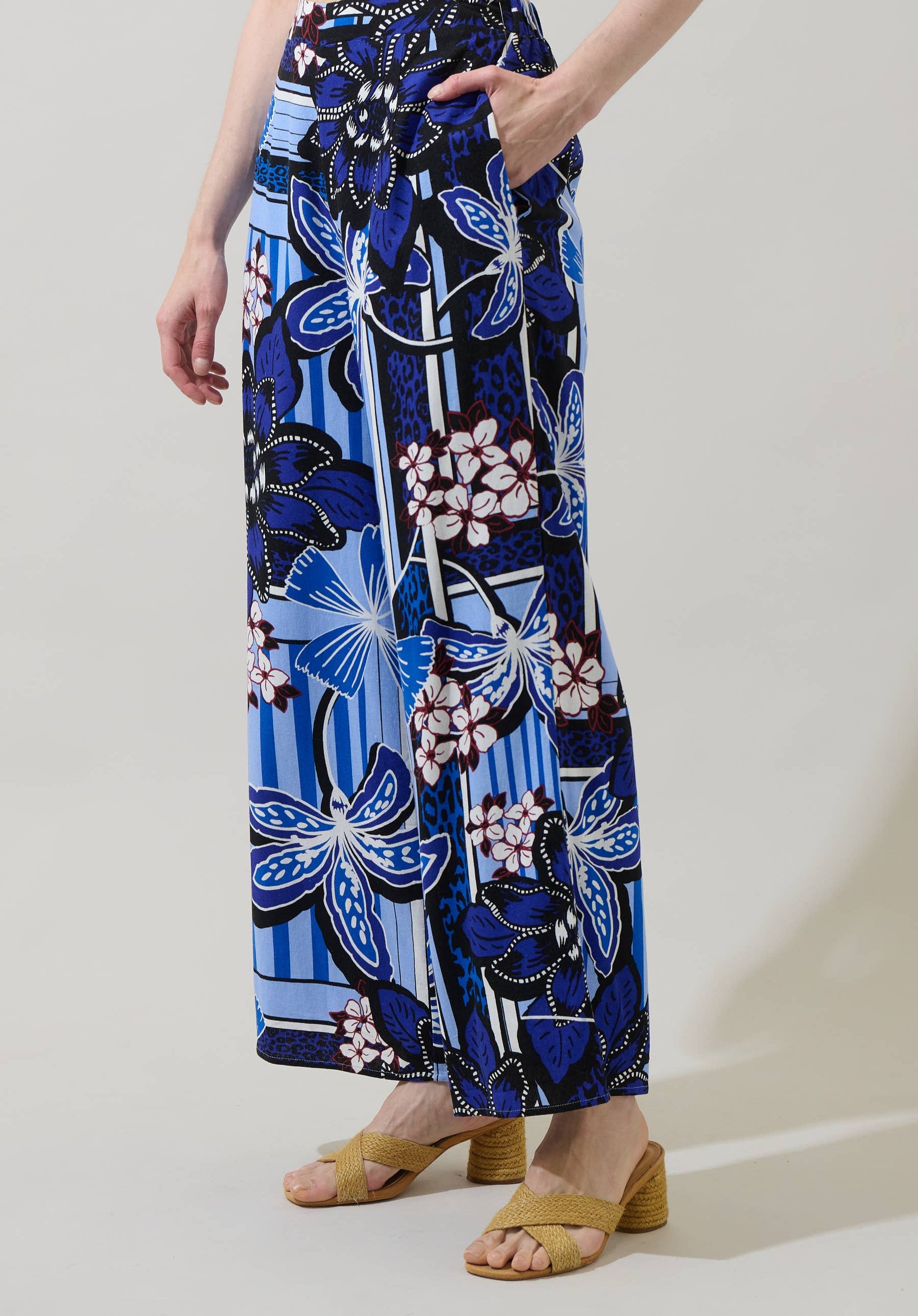 Person wearing a blue floral patterned skirt on a plain background