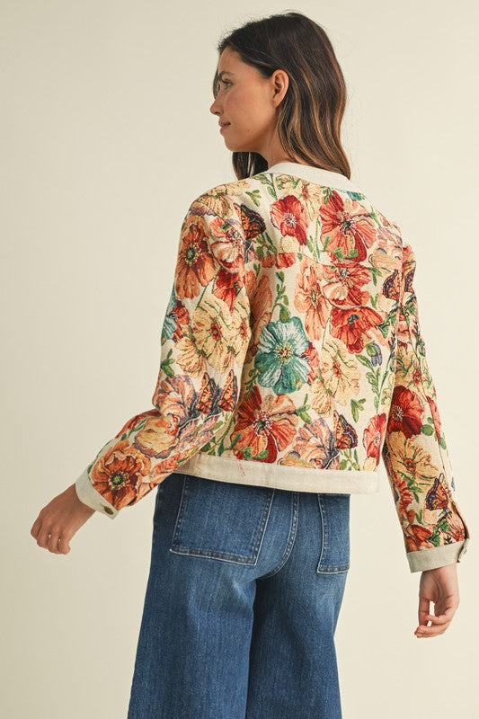 Woman wearing a colorful floral blouse and blue jeans on a beige background
