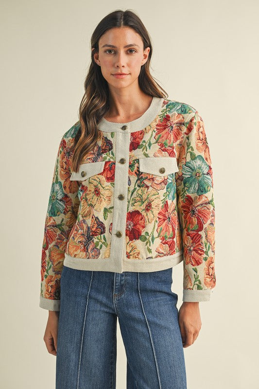 Woman wearing a floral jacket and blue jeans on a beige background