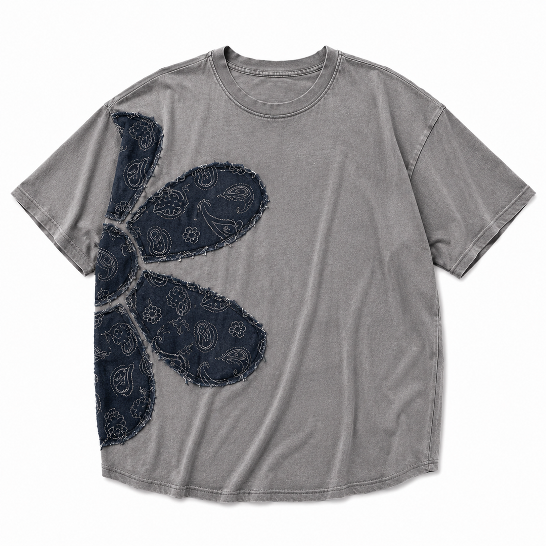 A gray mineral-wash short-sleeve t-shirt featuring a large dark navy blue paisley graphic on the front, laid flat against a white background.