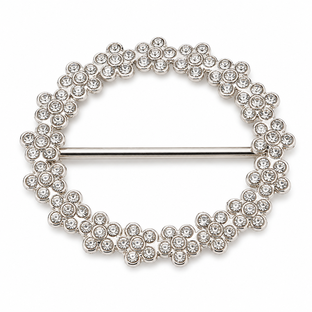 A silver-tone circular shirt cincher decorated with clear round crystals in a floral pattern, featuring a straight pin bar across the center, shown on a plain white background.