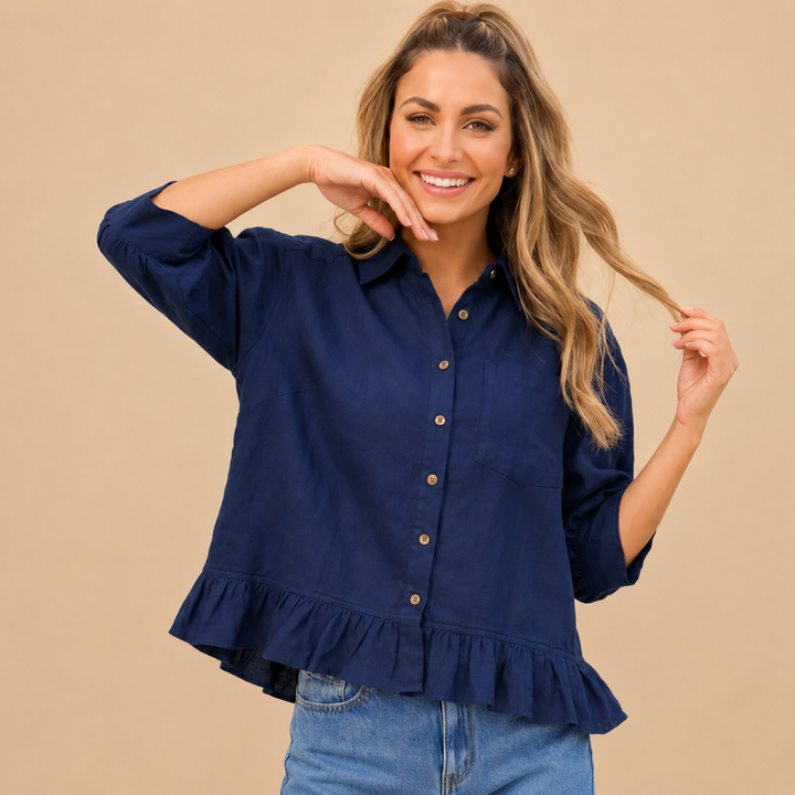 Woman wearing a navy blue blouse with ruffled details on a beige background