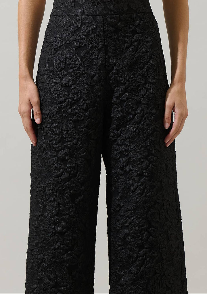 Black textured pants worn by a person on a plain background