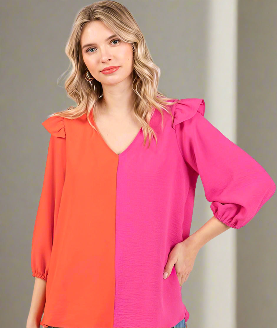 Woman wearing a colorful blouse with orange and pink sections on a white background