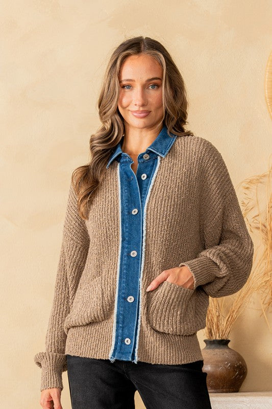 Woman wearing a brown knitted cardigan with a blue denim collar against a beige wall.