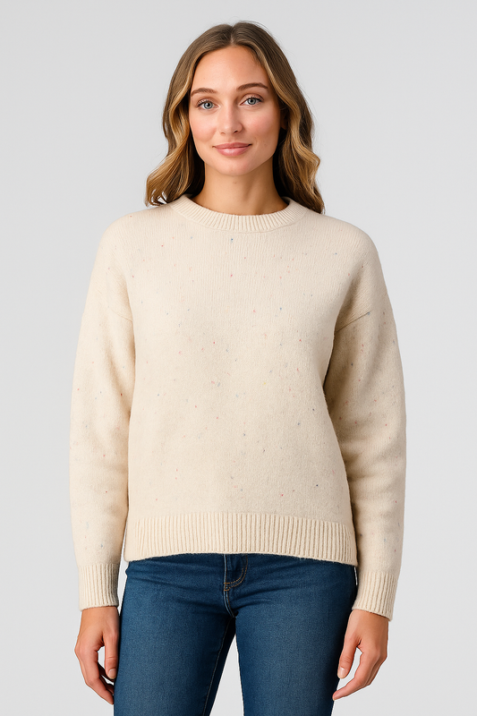 Woman wearing a beige sweater and blue jeans on a light gray background