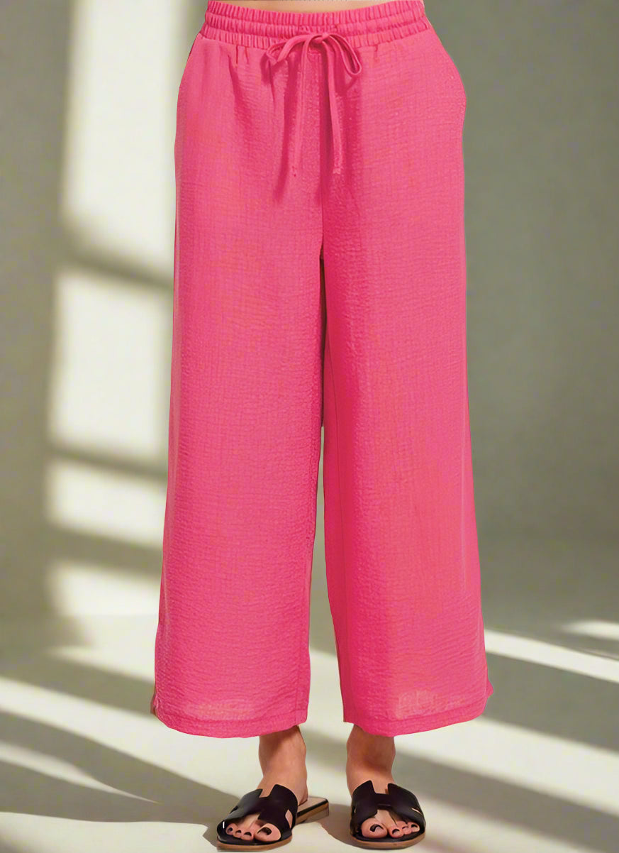 A pair of pink crepe pants with an elastic waistband and side pockets.