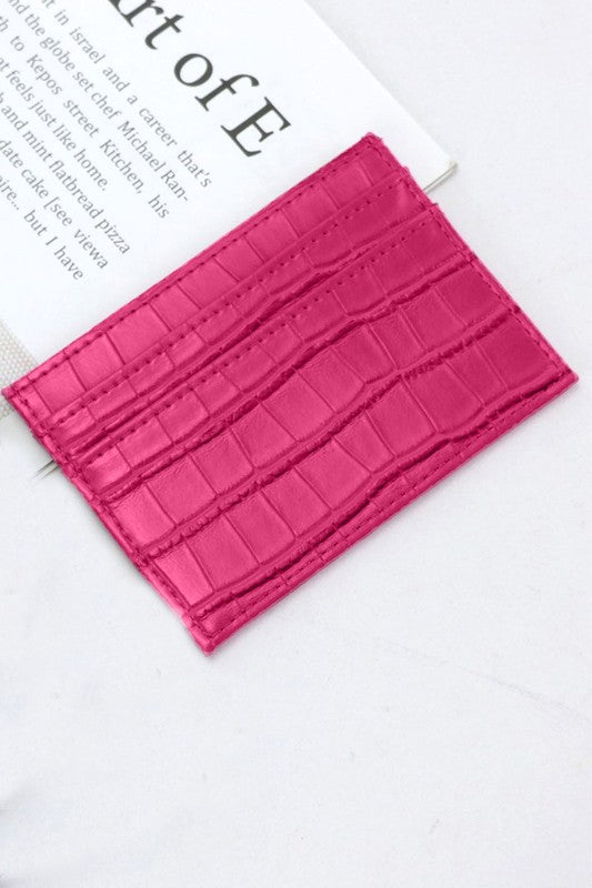Pink crocodile texture cardholder on a white surface with text in the background
