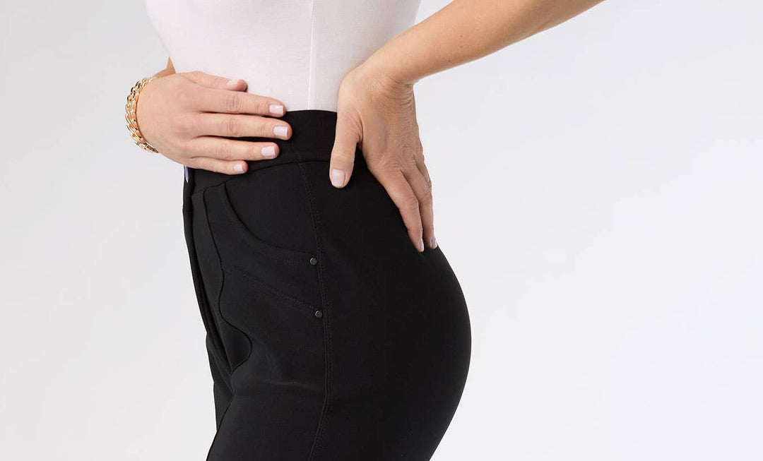 Person wearing black pants and beige heels on a white background