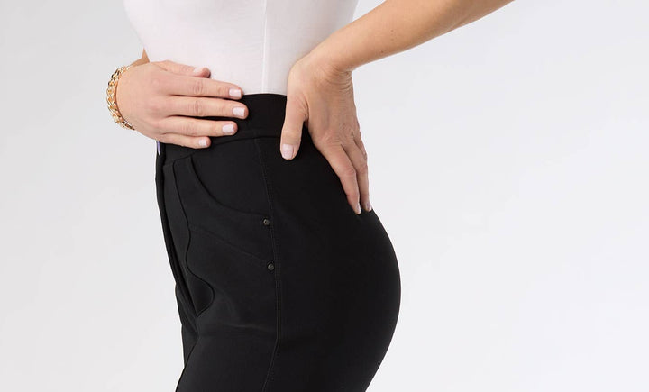 Person wearing black pants and beige heels on a white background