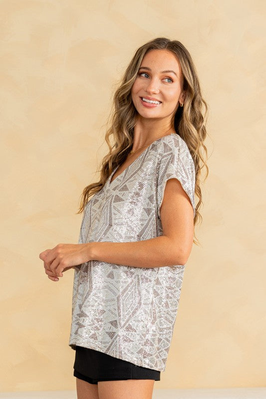 Woman wearing a patterned top and black shorts against a beige background