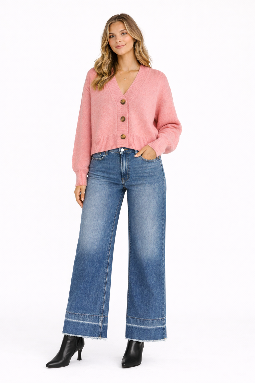 Woman wearing a pink cardigan and blue jeans on a white background