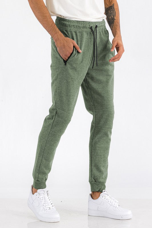 Person wearing green jogger pants and white sneakers on a white background