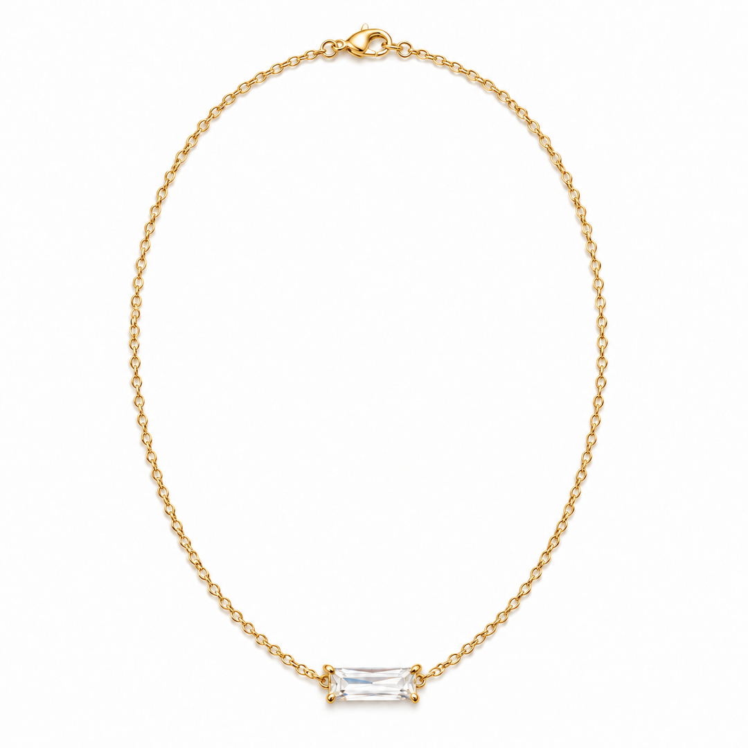 A delicate gold chain necklace with a small rectangular clear baguette-cut gemstone pendant, displayed on a clean white background.