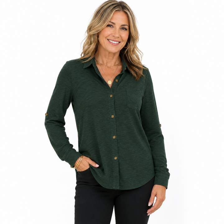 A woman modeling a dark forest green long-sleeve button-up shirt with brown buttons, paired with black pants, against a plain white background.