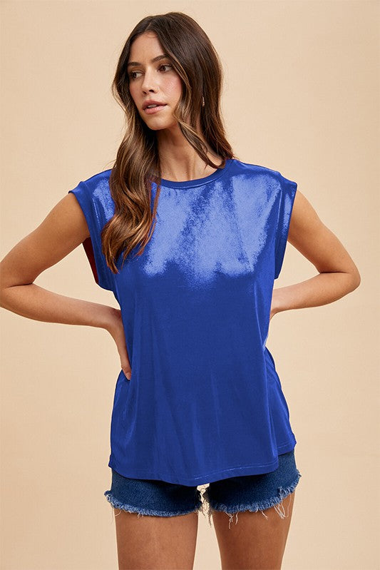 Woman wearing a blue sleeveless top and denim shorts on a beige background