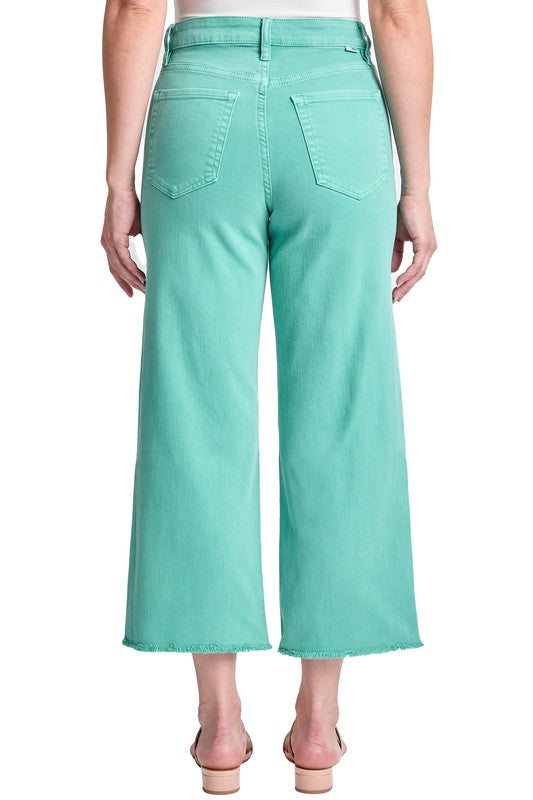 Person wearing teal pants on a white background