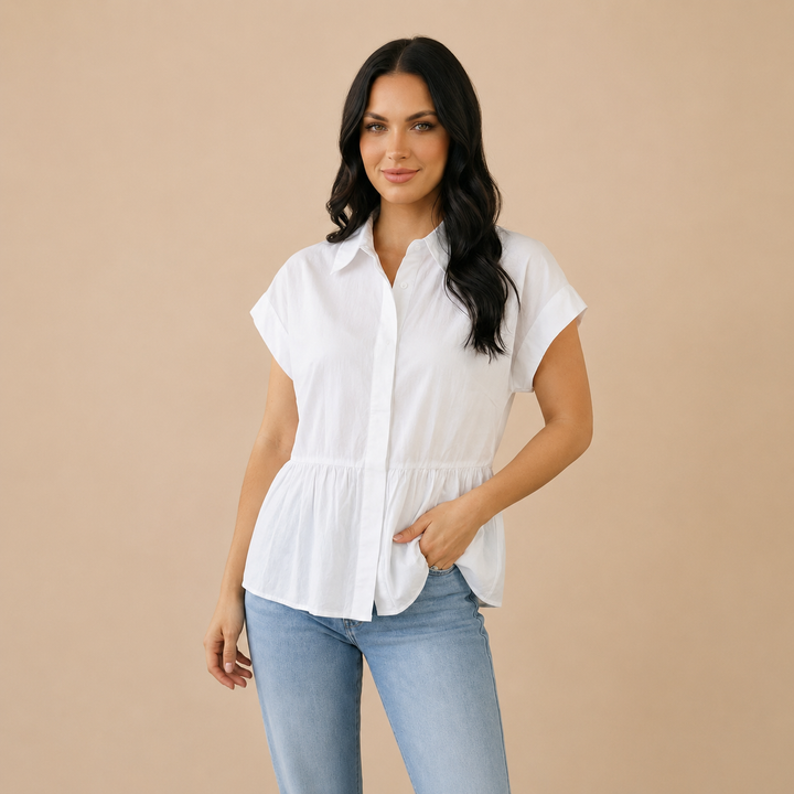 Woman wearing a white blouse and blue jeans against a beige background