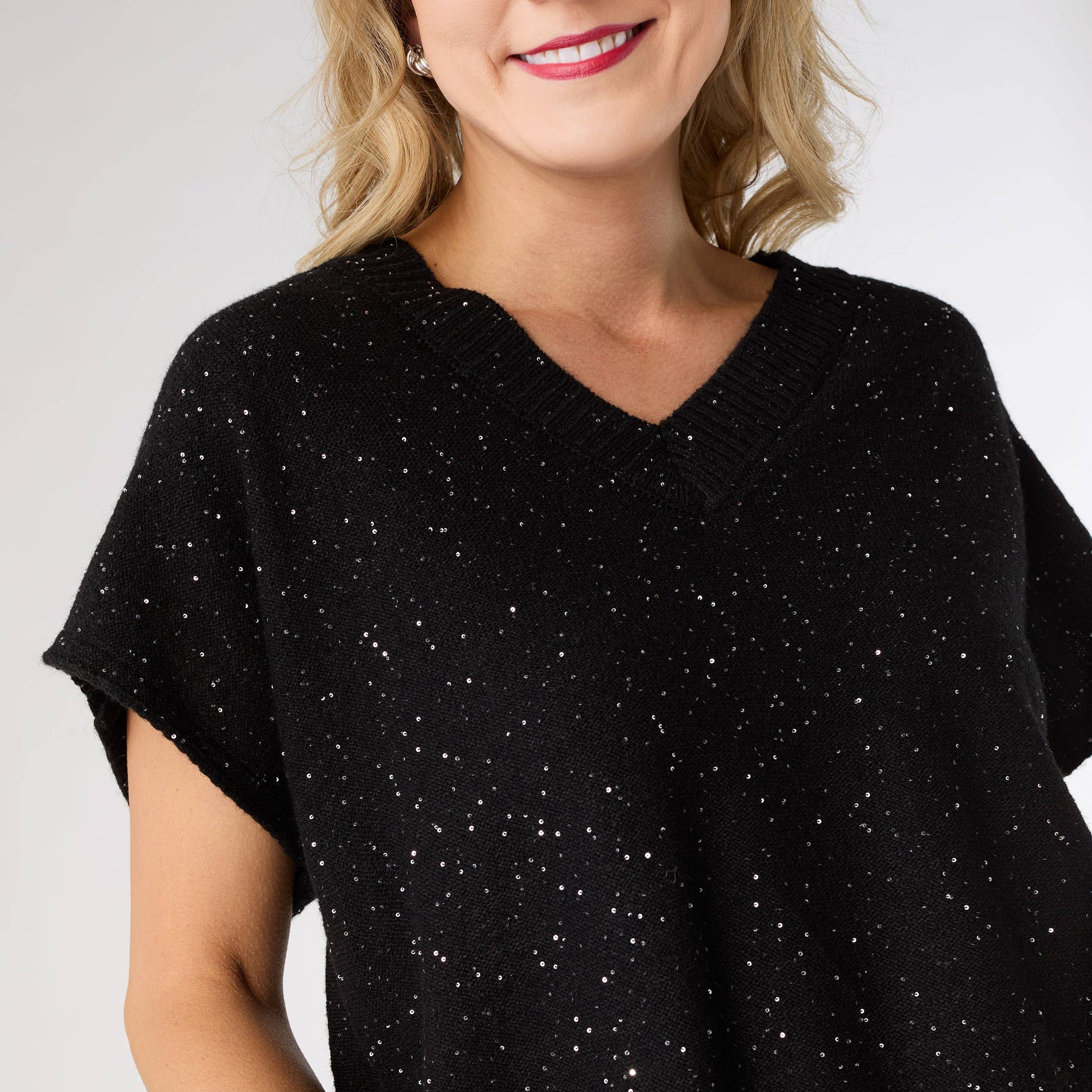 Woman wearing a black speckled shirt against a white background