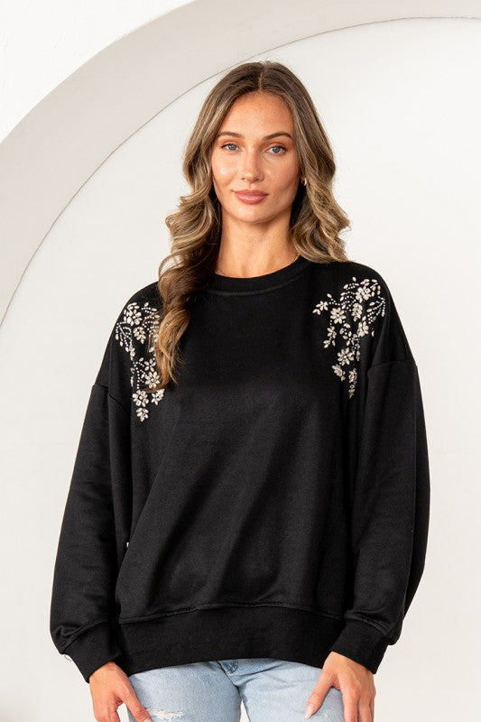 Woman wearing a black sweatshirt with floral patterns on a white background