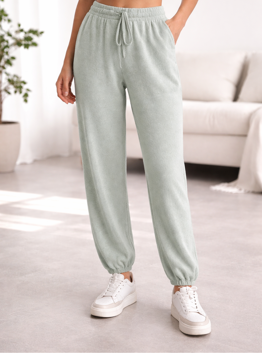 Person wearing light grey jade sweatpants and white sneakers in a room.