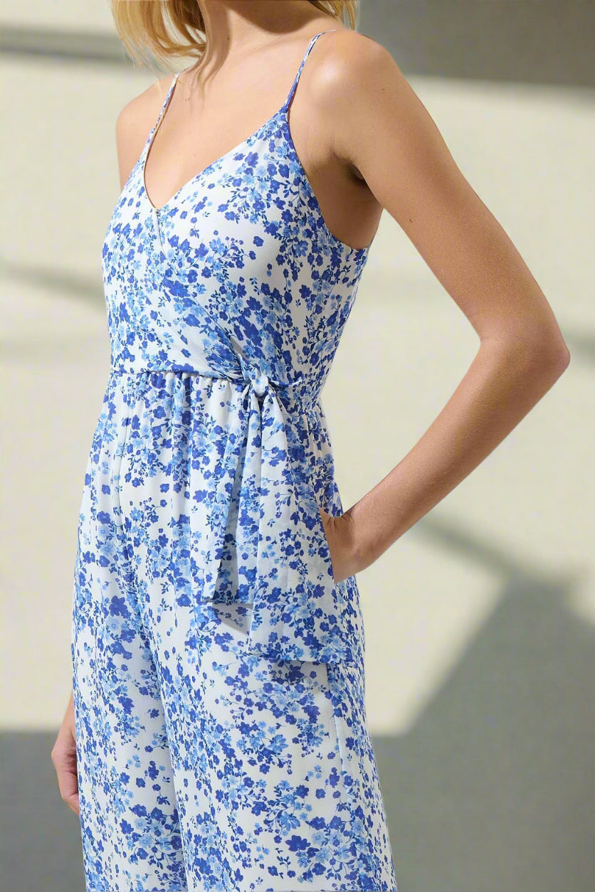 Woman wearing a blue floral JUMPSUIT against a neutral background