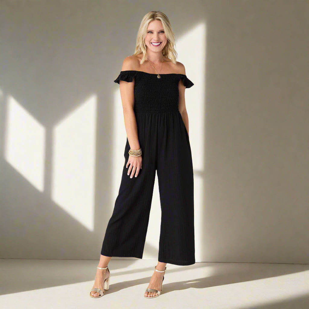 Woman wearing a black off-shoulder jumpsuit on a white background