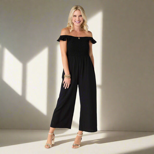 Woman wearing a black off-shoulder jumpsuit on a white background