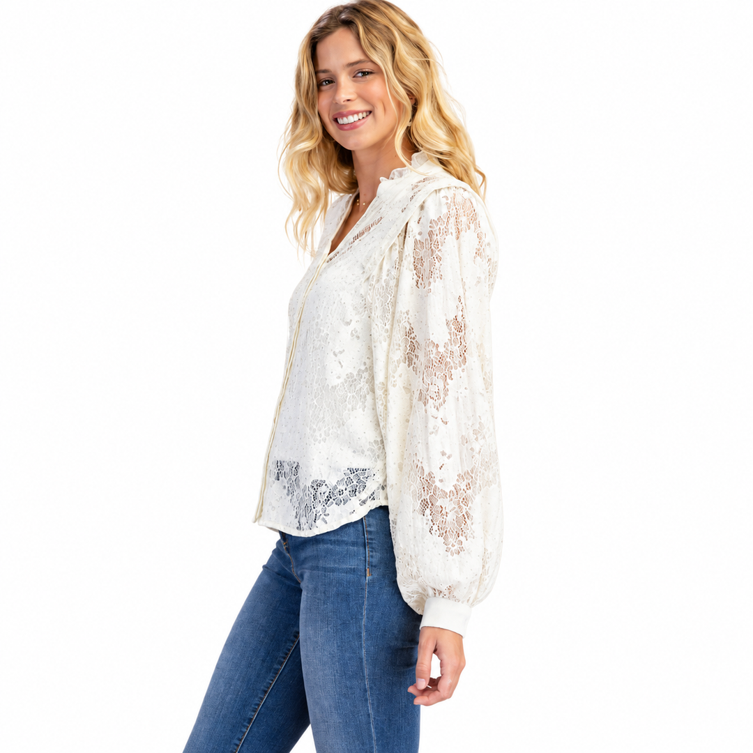 A woman modeling a white lace long-sleeve blouse with sheer puff sleeves and blue jeans against a plain white background.