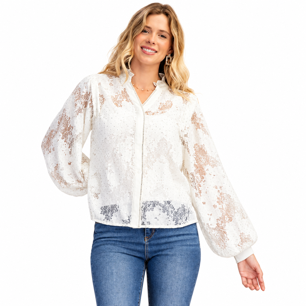 A woman modeling a white sequined jacket with sheer lace sleeves and blue jeans against a plain white background.