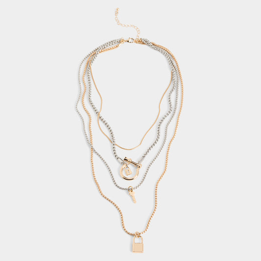 Stack of layered gold and silver necklaces on a light gray background