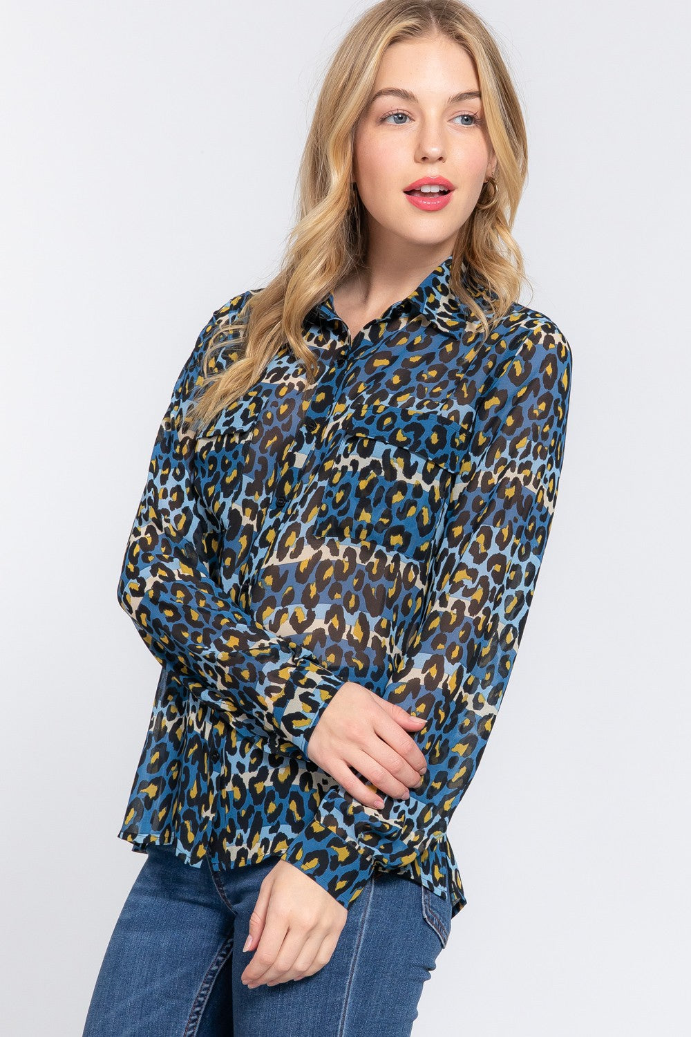 A woman wearing a blue and green leopard print blouse with long sleeves.