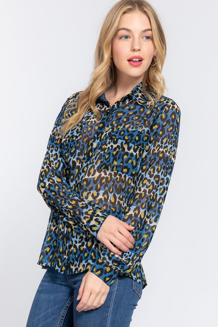 A woman wearing a blue and green leopard print blouse with long sleeves.