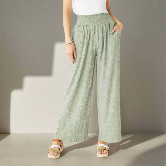 Person wearing light green wide-leg pants on a white background