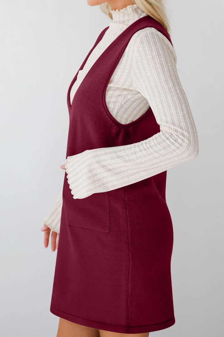 Maroon dress over a white sweater on a plain background