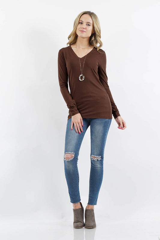 Woman wearing a brown long-sleeve top and blue jeans on a white background