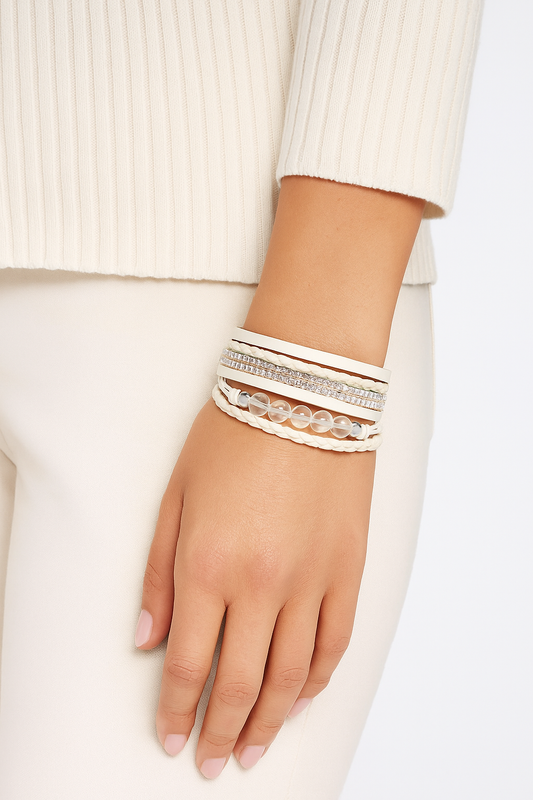 Hand wearing multiple bracelets on a plain background