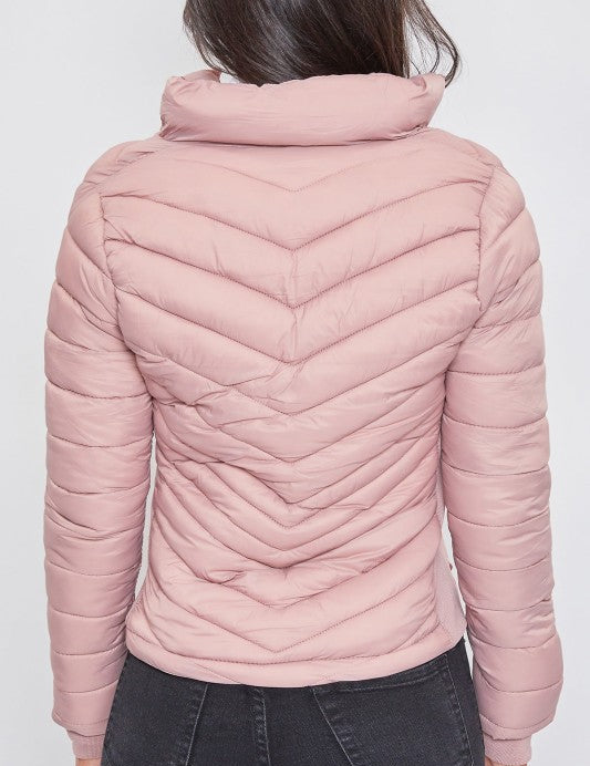 Pink quilted jacket worn by a person on a white background