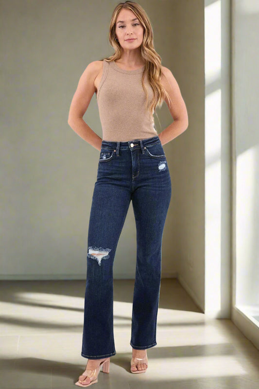 Woman wearing blue jeans and a beige tank top on a white background