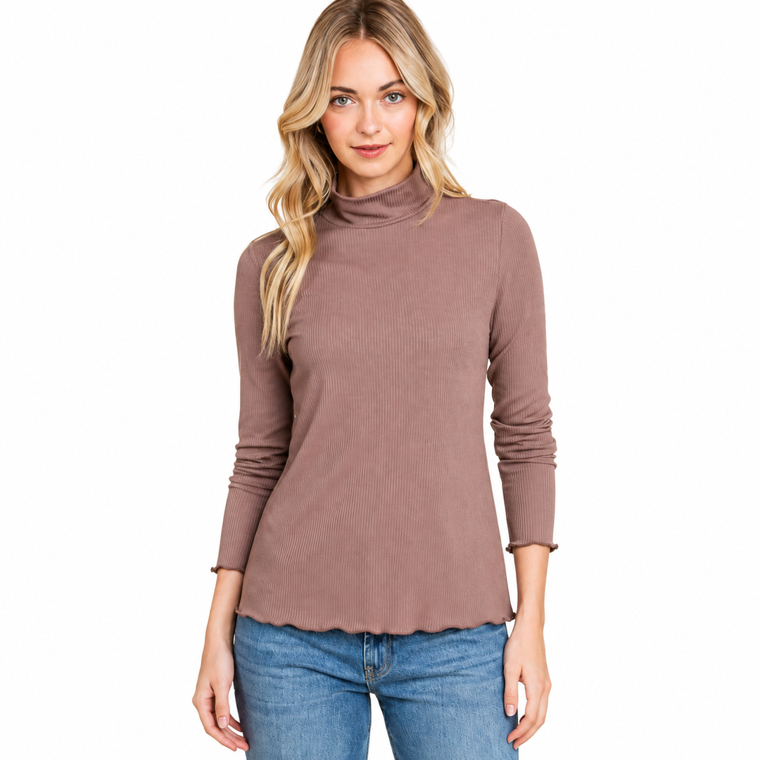 A woman modeling a ribbed, long-sleeve mock neck turtleneck top in a dusty mauve-brown color, paired with blue jeans, against a solid white background.