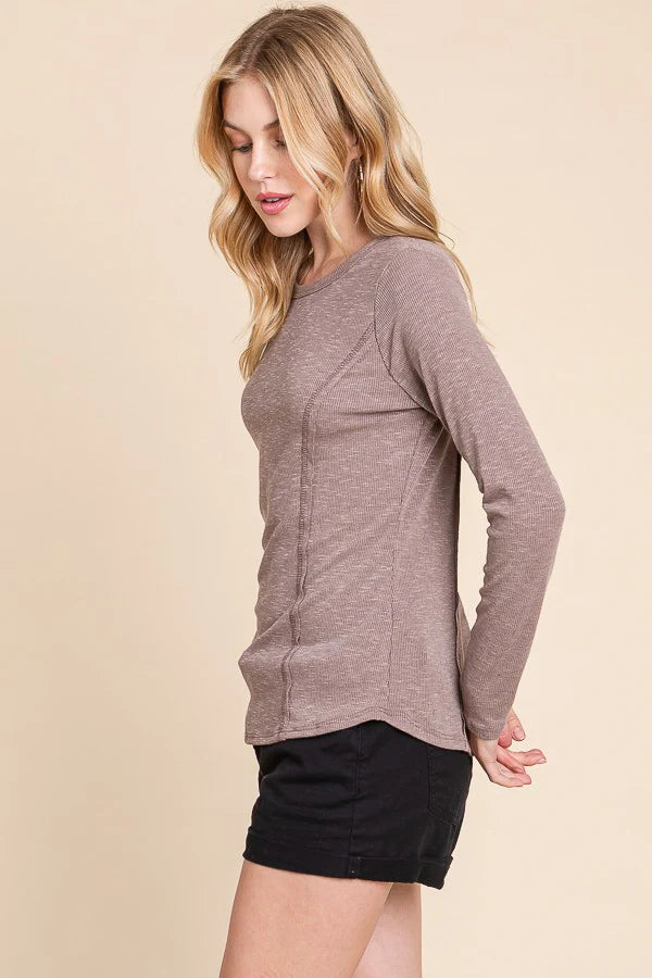 Woman wearing a brown long-sleeve top and black shorts on a beige background