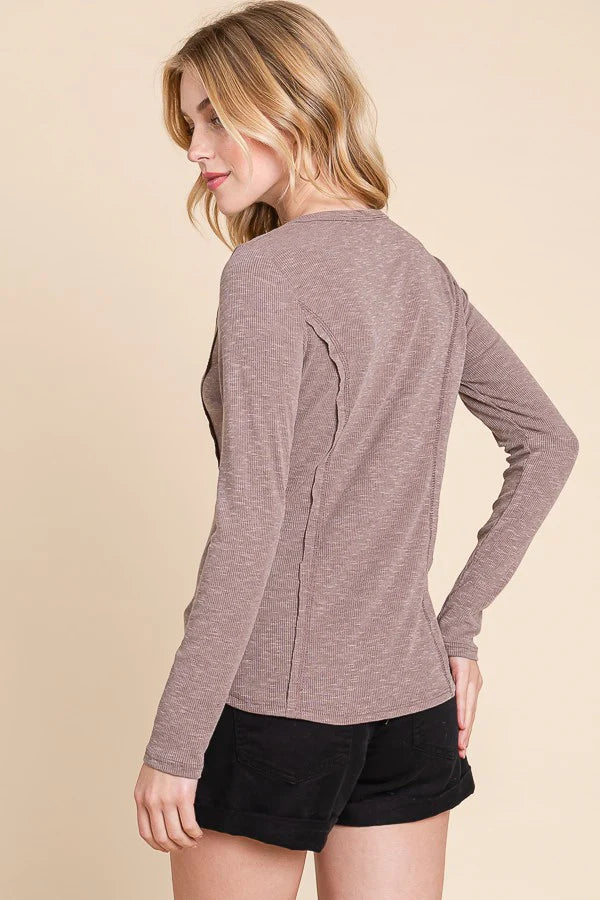 Woman wearing a brown long-sleeve top and black shorts on a beige background