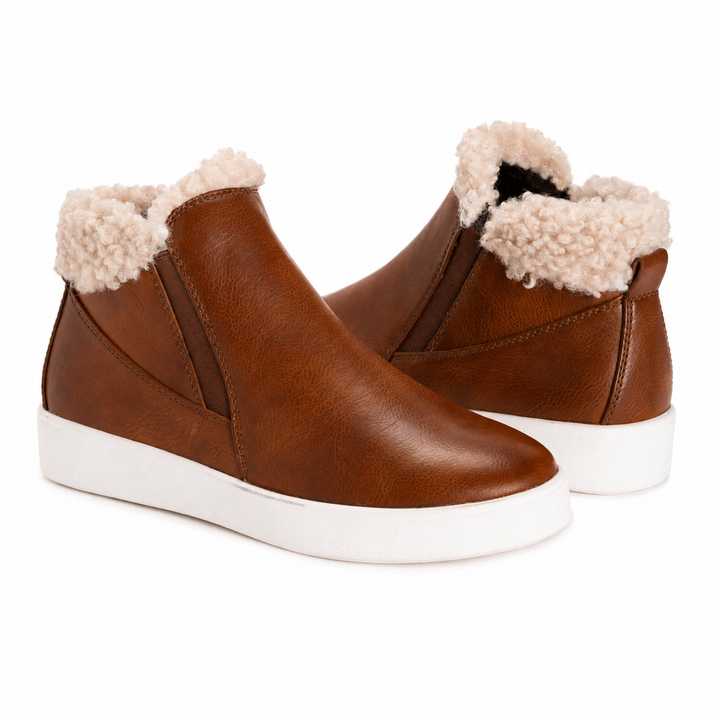 A pair of brown faux-leather slip-on ankle boots with a cream sherpa fleece lining and thick white platform soles, shown on a plain white background.