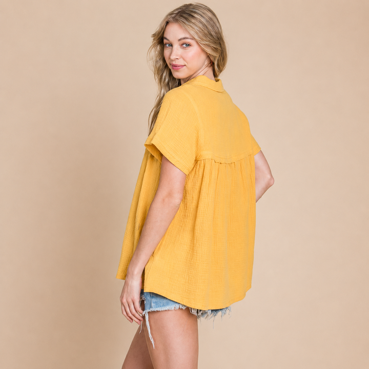 Woman wearing a yellow blouse and denim shorts on a beige background