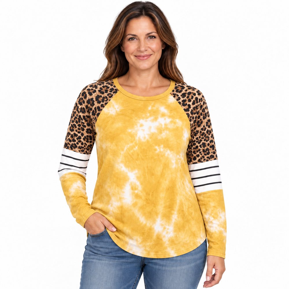 A woman modeling a long-sleeve raglan top with a yellow and white tie-dye body, leopard print sleeves, and white stripes on the cuffs, paired with blue jeans against a plain white background.