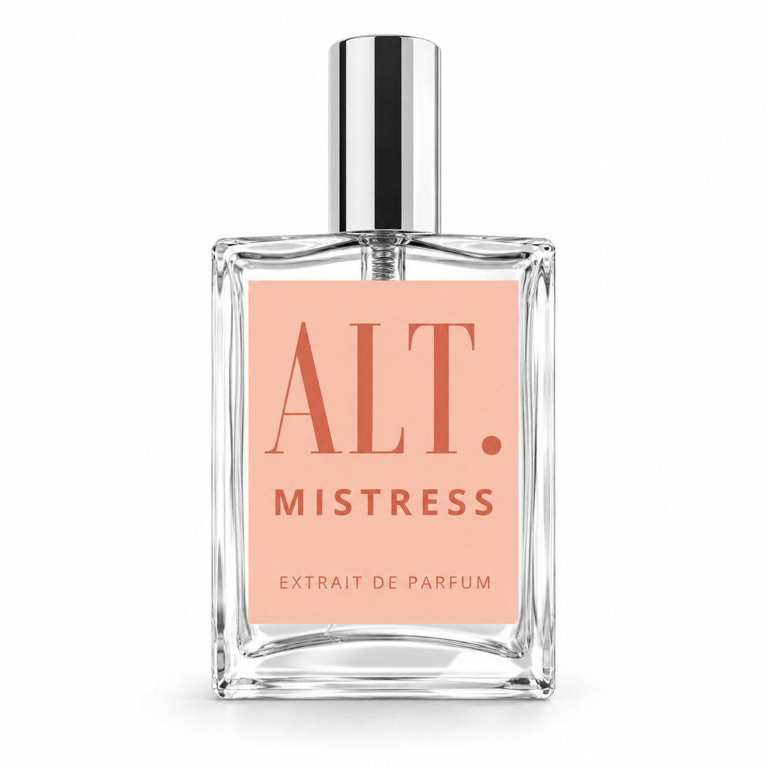 A clear glass perfume bottle with a rectangular shape, featuring a light peach-pink label with the text &