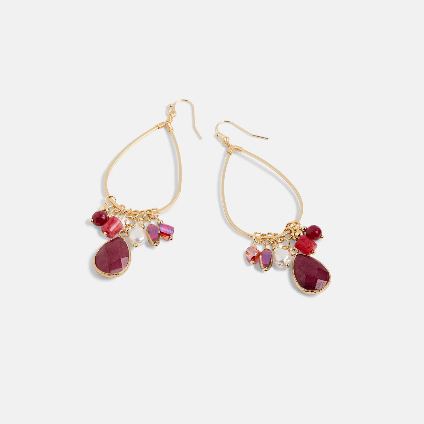 Gold earrings with red teardrop-shaped stones on a white background