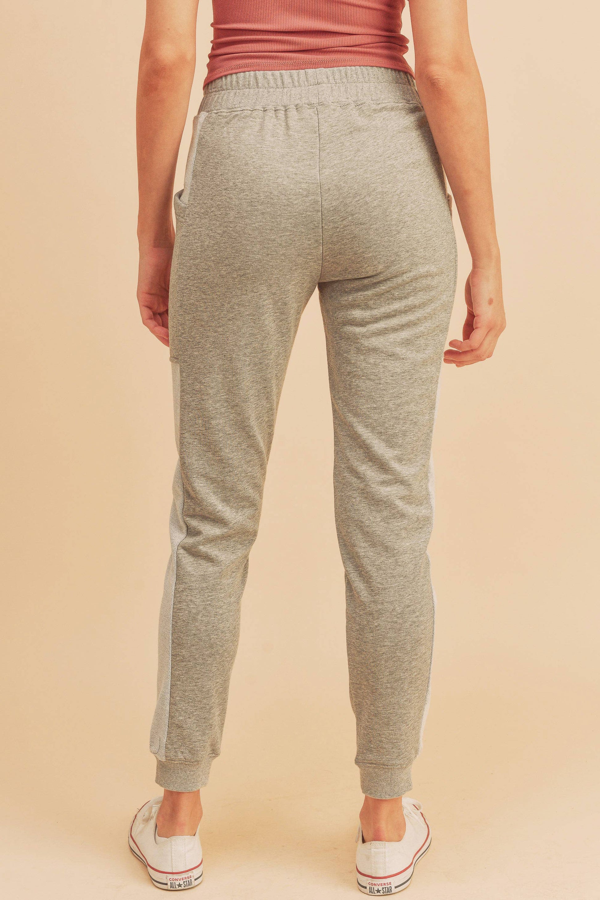 Person wearing gray sweatpants on a beige background