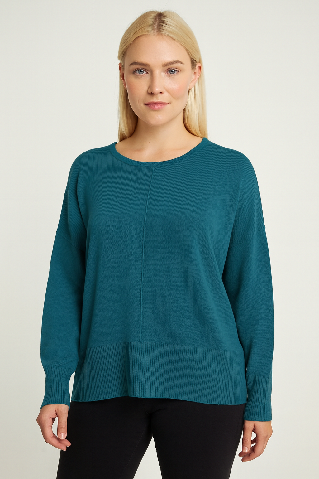 Woman wearing a teal sweater against a plain background